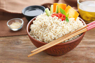 Bowl with brown rice and vegetables on wooden table