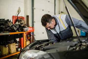 Car mechanic man at the garage fixing the engine.