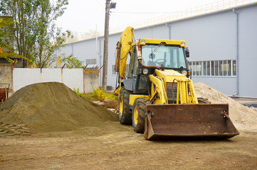 The concept of agronomy, a yellow tractor with a bucket demonstrates work