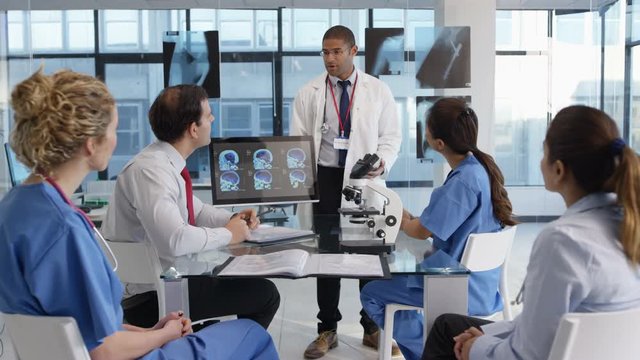  Medical team in a meeting, using technology to look at brain scans & x-rays.