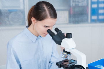 young woman scientific / female student researcher looking microscope  in a laboratory.