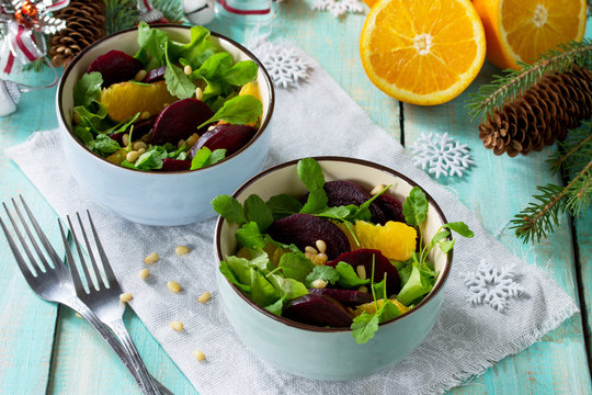 Homemade appetizer on a festive Christmas table. Salad with beets, orange, arugula and pine nuts.