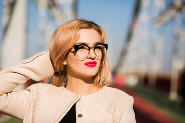 Lifestyle portrait of sexy blonde model with bright makeup wears trendy glasses. Space for text