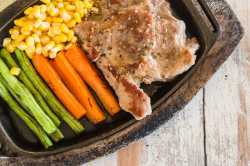 Pork steak with vegetable. Corn, carrots, green beans, on wooden table background.