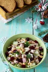 Homemade appetizer on a festive Christmas table. Salad with beets, Peking cabbage, meat and beans.