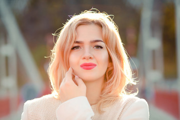 Closeup portrait of beautiful blonde model with bright makeup and perfect skin posing in sunny day