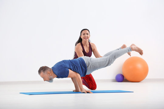 Mature man with personal yoga instructor indoors