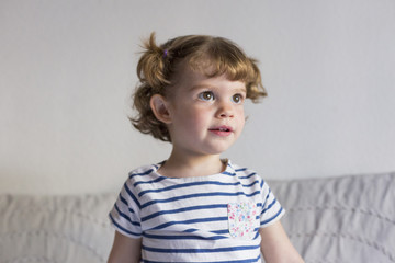Fototapeta premium beautiful little girl standing on bed and smiling. Fun, home, indoors. Lifestyle