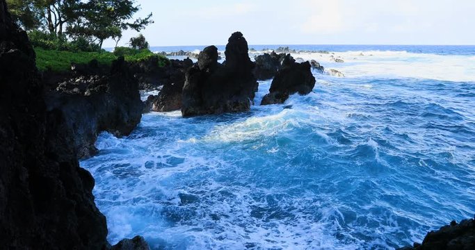 Volcanic rock coast violent waves surf pound shore Hawaii. Big Island. Economy is tourism based. Water and tropical beach recreation and fun. Beautiful clear blue ocean sea.