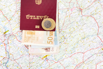 The Hungarian passports and euro banknotes on a geographical map, focus on coins