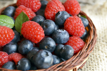 Fresh organic blueberries and raspberries.
Freshly picked raspberries and blueberries in a basket on a burlap cloth background.Blueberry and raspberry.Healthy eating,diet concept.Selective focus.