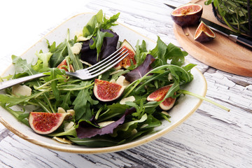 Autumn salad of arugula, figs in a white earthenware plate.