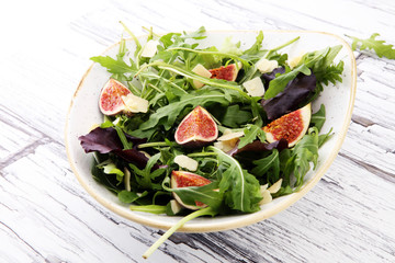 Autumn salad of arugula, figs in a white earthenware plate.
