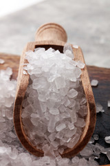 sea salt with wooden spoon and crystals of salt on wooden background.