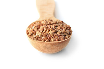 Raw buckwheat in wooden spoon on white background