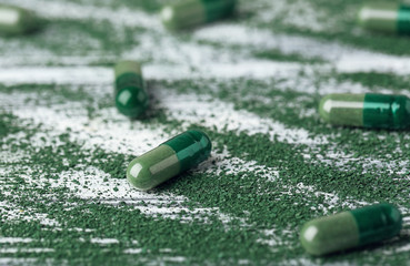 Spirulina capsules with powder on table
