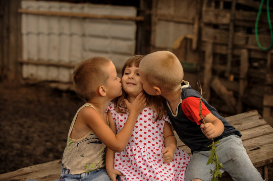 The Italian girl came to a pig farm to two Russian boys. The boys kiss and hug the girl. The concept of friendship of peoples.