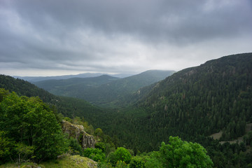 France - Rocky valley in forest and wooded landscape with rain clouds