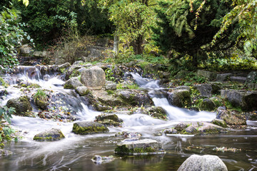 long exposure photo of a small waterfall falling down the stream