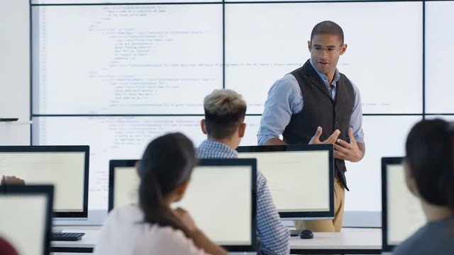  Students working on computers & listening to teacher in adult education class