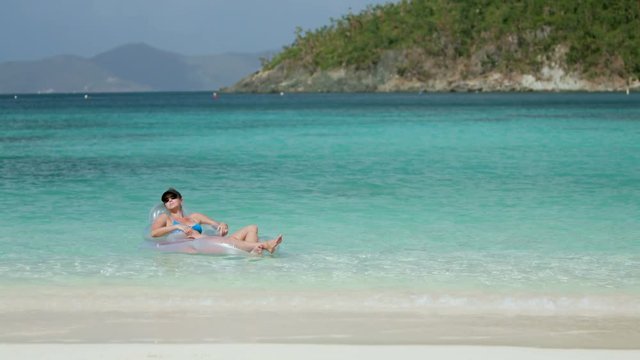 woman relaxing in raft on tropical beach, honeymoon beach, st john 