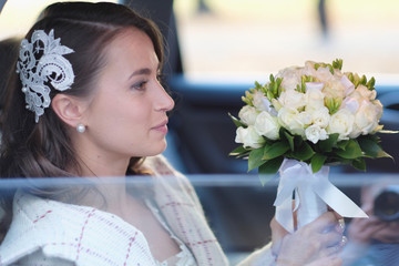 Portrait of a bride in a wedding limousine with a bouquet of flowers