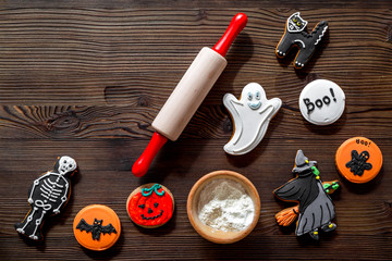 Cook halloween gingerbread cookies in shape of skeleton, mummy. Sweets near desk and rolling pin. wooden background top view copyspace