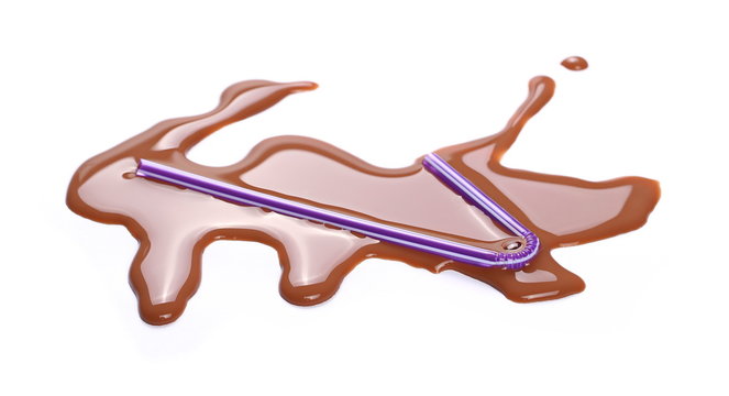 Spilled chocolate milk puddle with purple straw isolated on white background