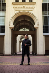 Serious and confident businessman looking away against the background of an old architectural arch.