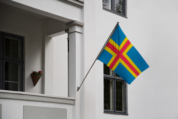 &Aring;land Islands flag.  &Aring;land flag displaying on a pole in front of the house. National flag of  Aland Islands waving on a home hanging from a pole on a front door of a building.