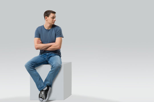 Man sitting on a cube and looking away - isolated