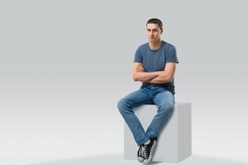 young man sitting on white cube. isolated