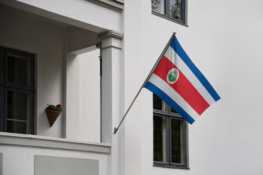 Costa Rica flag. Costa Rican flag displaying on a pole in front of the house. National flag of  Costa Rica waving on a home hanging from a pole on a front door of a building.