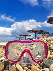 Mask for scuba diving on a pebble beach. Underwater masks and tubes in the water on pebbles on the sea coast. The concept of a dive or the concept of a summer sea voyage. Equipment for diving. © kravik93