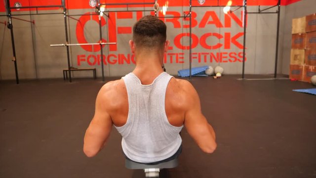 Back view of male athlete training on rowing machine