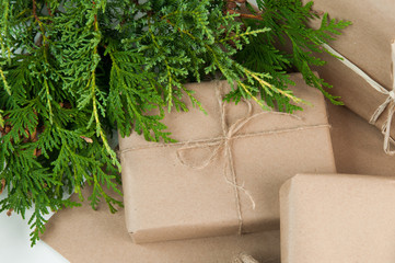 presents wrapped in brown paper on a white background with greenery