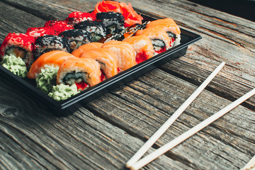 on a wooden table in the black container are nicely decomposition sushi