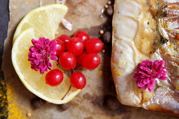 Roasted grilled fish, cheese, honey, rowan, kalina, lemon slices, baked potatoes, pink flowers, turmeric and mustard seeds on vellum paper in retro style
