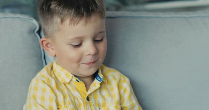Close-up of the child holds the remote control from the TV boy ooking sideways home child happy kid lifestyle face, home play alone laugh mood Shot on RED EPIC camera. Slow Motion Shot.