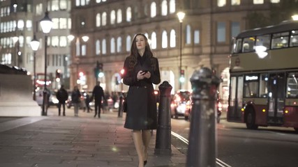  Young woman looking at smartphone & flagging down a cab in the city