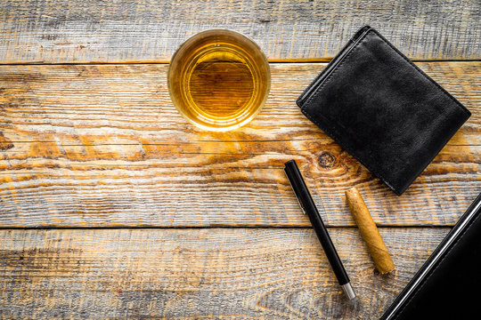 Drink whiskey in the evening. Glasses, wallet, cigar on rustic wooden background top view copyspace
