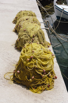 Three piles of fishing nets on the edge of a harbour