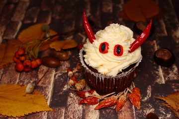 Cake on Halloween - evil. The idea of baking and decorating for Halloween. Cake for Halloween in the form of the devil with horns made of red pepper. He stands on an imitative stone wall. 