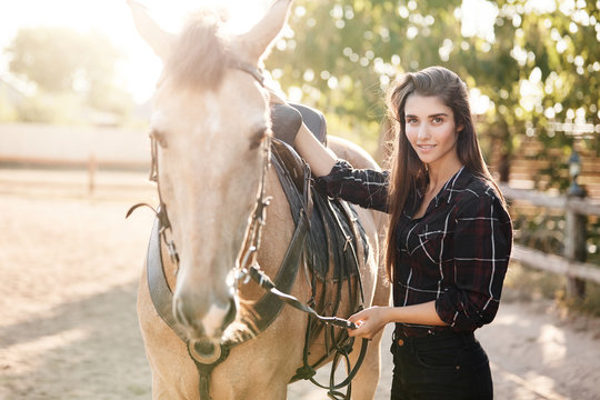 Portrait of beautiful posh long haired female farm owner. Woman running a succesful breeding business petting a horse.