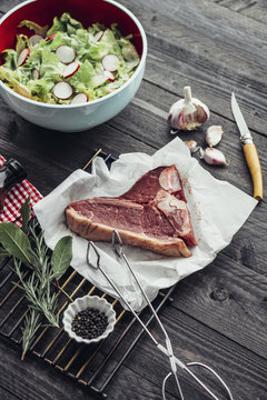 Food: Barbecue ingredients on dark wood with T-Bone Steak and salad