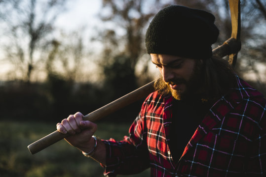Young lumberjack walking with pickaxe on the shoulder