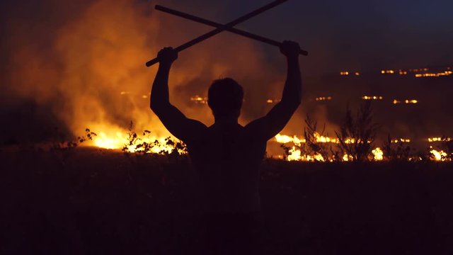 Dark silhouette of man on the burning background. 4K