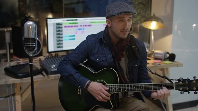  Young musician playing guitar & singing in home recording studio