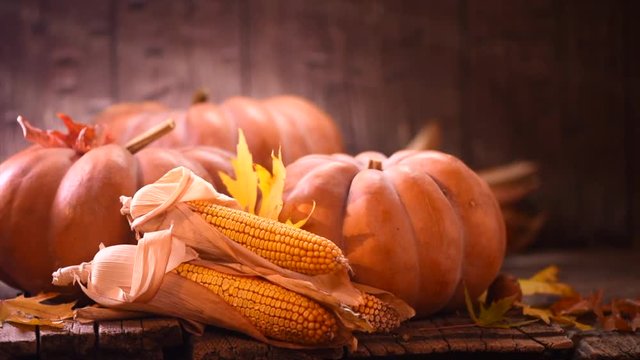 Thanksgiving Day. Wooden table decorated with pumpkins, corn combs, candles and autumn leaves. 4K UHD video 3840x2160