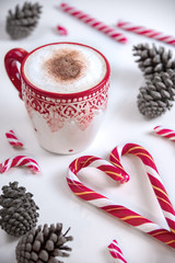 Cup of coffee with heart shape christmas candy and pines on white background.